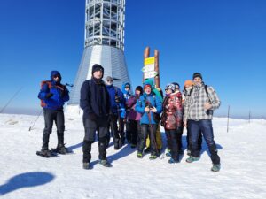 Na zdjęciu grupa osób pod szlakowskazem na szczycie Śnieżnika w zimie