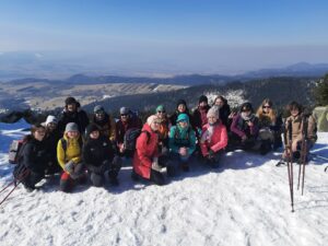 Grupa osób pozuje do zdjęcia na tle gór pokrytych śniegiem.