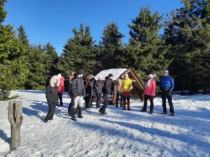 Na zdjęciu grupa osób grając a wgrę baba jaga patrzy w zimie w lesie.
