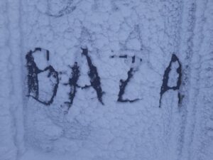 Na zdjęciu zamarznięta szyba pokryta śniegiem z wyrytym napisem BAZA.