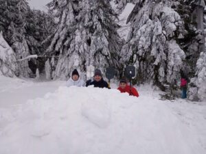 Na zdjęciu 3 mężczyzn ukrytych za usypaną ze śniegu górką. Zza górki wystają również pionowo łopaty