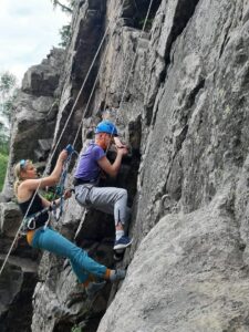 na zdjęciu chłopak wspinający się w skałach na wędkę razem z instruktorką wspinaczki