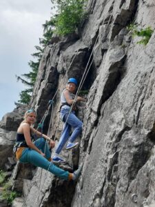 na zdjęciu dziewczyna wspinająca się w skałach na wędkę razem z instruktorką wspinaczki.
