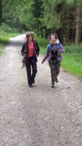 na zdjęciu 2 dziewczynki idące z plecakami po szutrowej drodze w lesie
