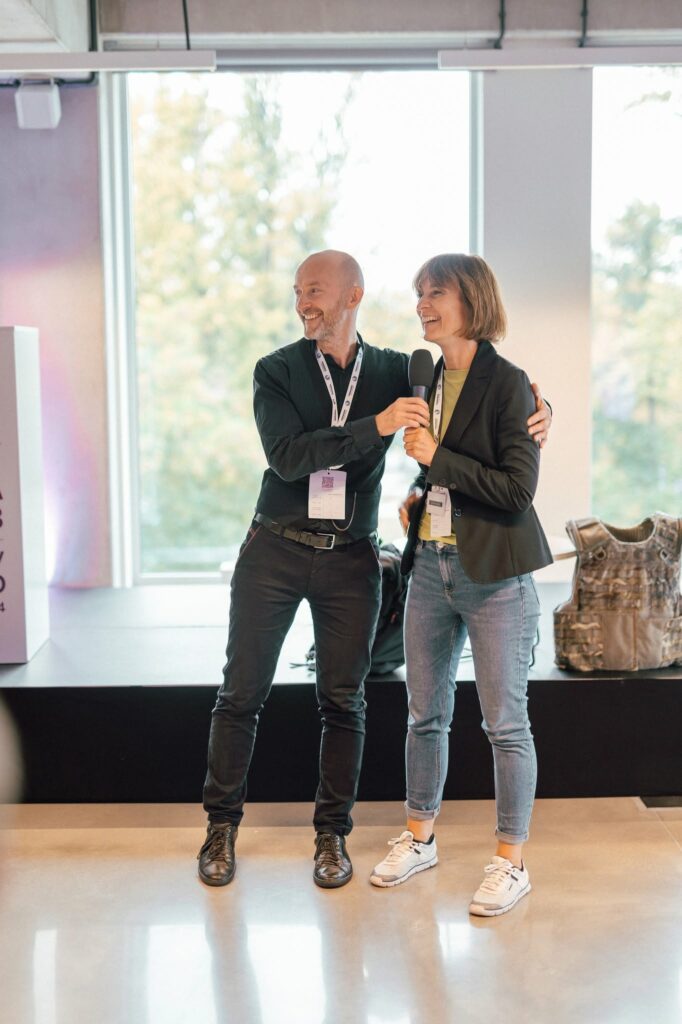 Sala konferencyjna. Na scenie stoją uśmiechanięci Piotr Kuźniak i Magdalena Stempska z Fundacji Imago.