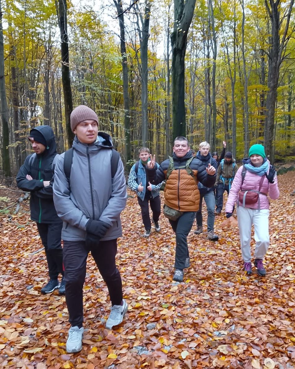 Ośmioosobowa grupa idzie przez las. Zdjęcie wykonane jesienią.