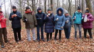 na zdjęciu 5 osób pozujących do zdjęcia w lesie, wszyscy są w kurtkach, jest jesień.