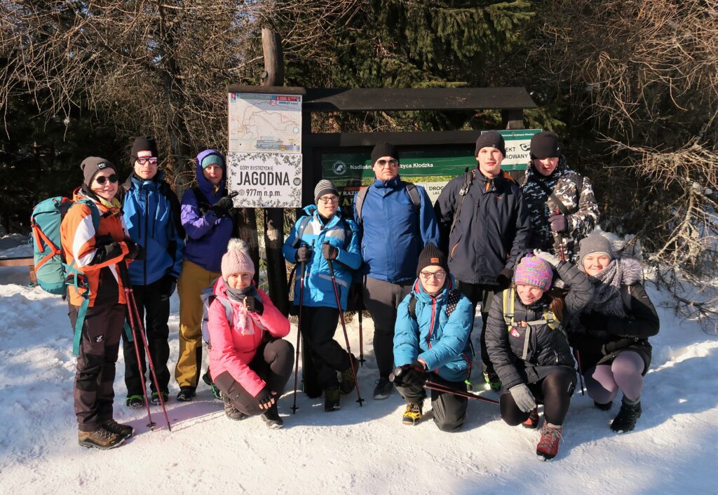 A group of people smiling after reaching the mountain top.