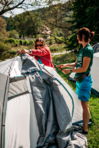 Na zdjęciu dwie kobiety rozkładają namiot