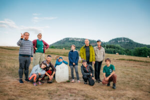 Zdjęcie grupowe przedstawiające młodych ludzi na tle gór przy pomniku w Pasterce