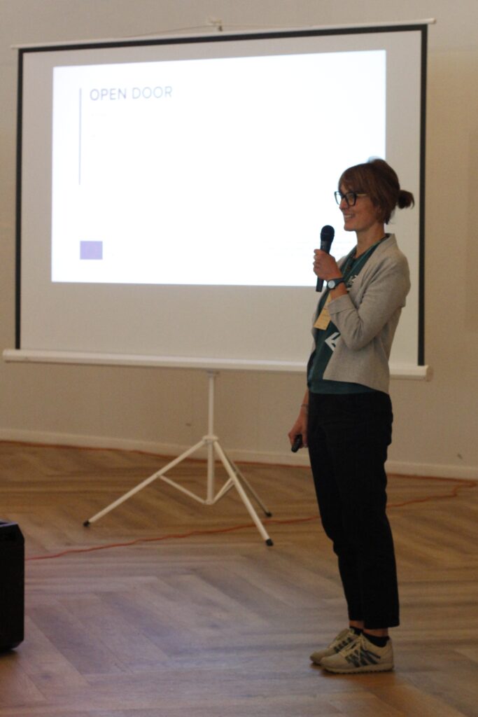Magda Stempska z Fundacji Imago wygłasza prelekcję w sali konferencyjnej, czasie konferencji "Natura bez Barier". Za jej plecami duży ekran z wyświetlającą się prezentacją.