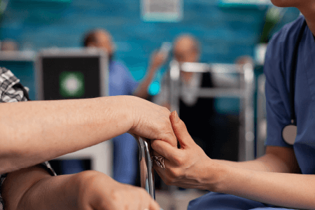 Dłonie dwóch osób. Jedna z nich ściska dłoń drugiejw geście wsparcia.