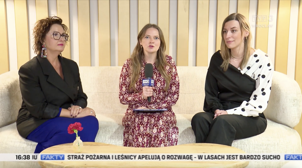 Skrin z ekranu komputera - kadr z programu "Popołudniówka z Faktami". Na zdjęciu na kanapie reporterka - Joanna Pietkiewicz z mikrofonem TVP, po jej obu stronach siedzą rozmówczynie - Martyna Rangno z Fundacji Imago oraz Beata Hernik-Janiszewska z Wrocławskiego Hospicjum dla Dzieci.