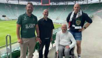 Zdjęcie wykonane na stadionie. Na zdjęciu są cztery osoby, które pozują do fotografii: Piotr Kuźniak i Łukasz Siemież z Fundacji Imago oraz Mateusz Jankowski i Marcin Ciarkowski z WKS Śląsk Wrocław.