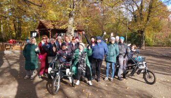 Grupa robocza projektu Mam tę moc pozuje do zdjęcia w parku, z rowerem - tandemem Fan tu goł.