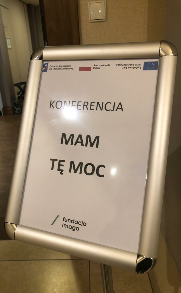 Korytarz z tabliczką informującą o konferencji “Mam Tę Moc”.