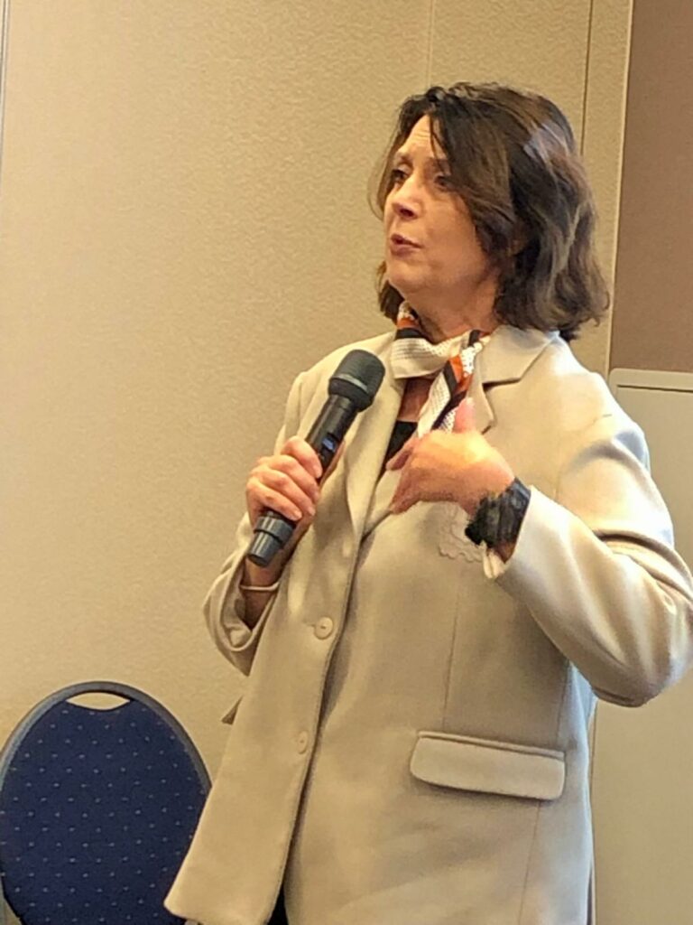 Profesor Aldona Wiktorowska-Święcka w trakcie swojego wykładu, z mikrofonem w sali konferencyjnej.