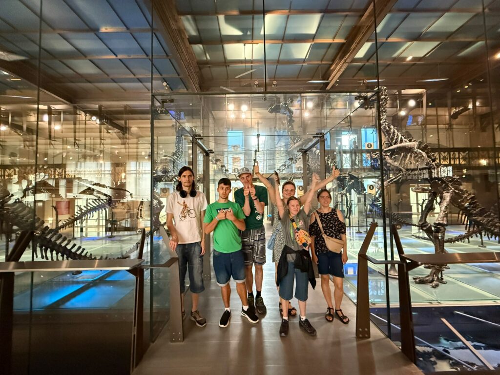 Grupa reprezentująca Polskę w projekcie Points of konekszyn sfotografowana w Muzeum Historii Naturalnej w Brukseli. Pozują do zdjęcia przy szkieletach dinozaurów.