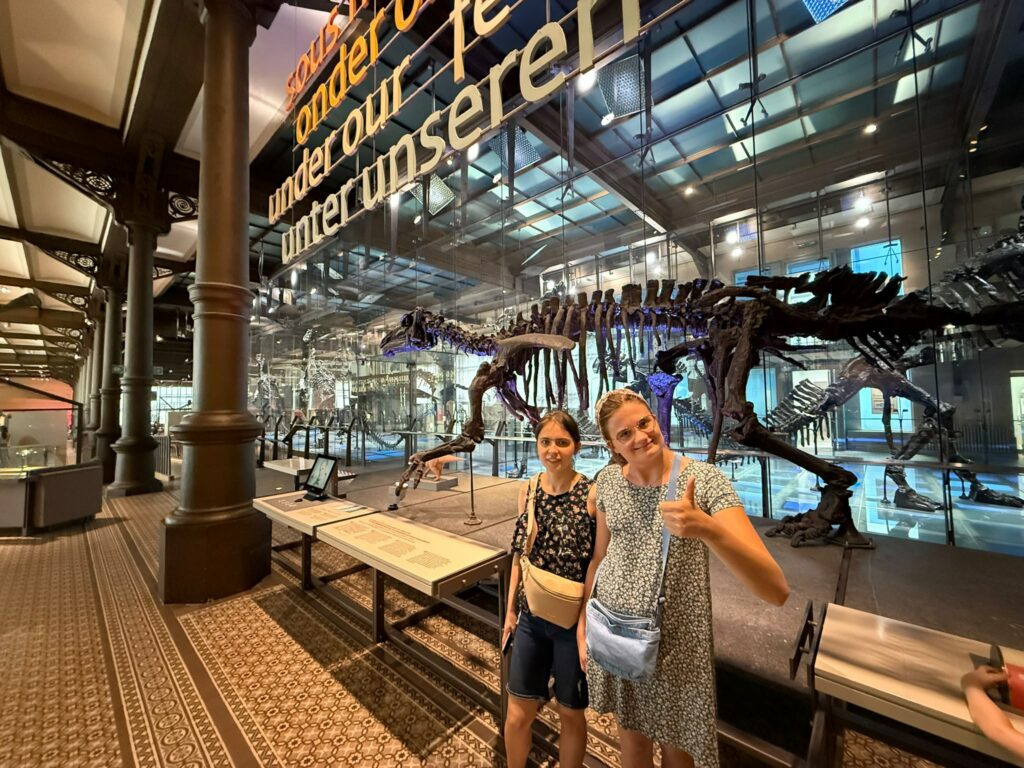Dwie uczestniczki polskiej grupy projektu Points of konekszyn pozują do zdjęcia w Muzeum Historii Naturalnej w Brukseli przy szkielecie dinozaura.