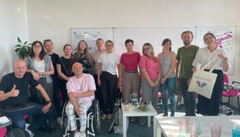 Uczestnicy wizyty studyjnej w Czechach pozują do wspólnego zdjęcia w sali szkoleniowej. Na fotografii jest 13 osób, wśród nich Magda Kowalska, Natalia Rojek i Łukasz Siemież z Imago.
