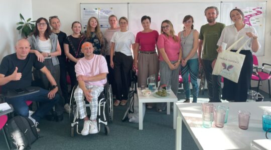 Uczestnicy wizyty studyjnej w Czechach pozują do wspólnego zdjęcia w sali szkoleniowej. Na fotografii jest 13 osób, wśród nich Magda Kowalska, Natalia Rojek i Łukasz Siemież z Imago.
