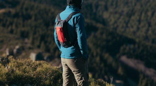 Mężczyzna w ubraniach trekkingowych na tle gór. Jest odwrócony plecami do zdjęcia.